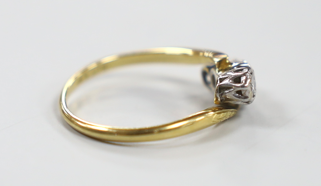An 18ct, pt and illusion set three stone diamond crossover ring, size M, gross weight 2.7 grams.